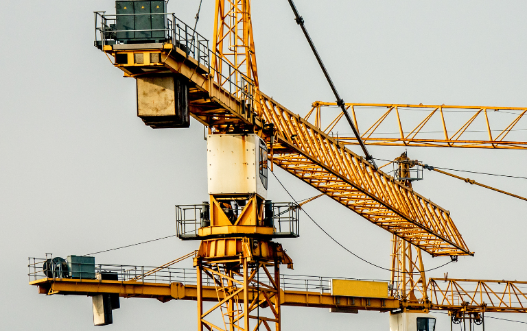 Gelber Baukran auf Werksgelände – Elox Technik bietet Verkauf von neuen und gebrauchten Kranen